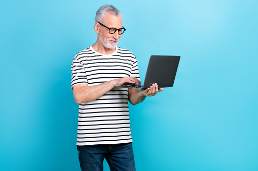 Photo portrait of funny old male showing laptop apple macbook samsung dressed stylish striped garment isolated on blue color background