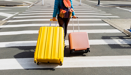 Young tourist woman holding the luggage as crosswalk to travel  trip in the Airport