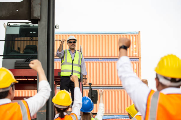 istock Logistic manager giving public speech and showing support to construction worker at container warehouse. Leader announcing good news. Successful corporate people and business. 1650228972