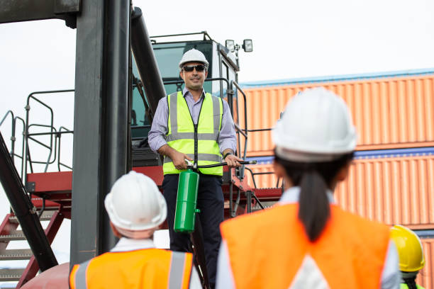 istock Manager training and showing staff worker to use fire extinguisher at the construction site. Man standing or forklift truck and explain to employee 1650229532