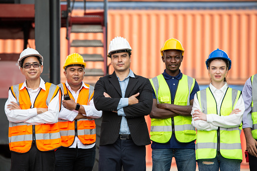 Group of team logistic worker and manager standing in arms crossed at container warehouse. Confidence and successful teamwork, corporate business of industrial factory. vision and mindset concept