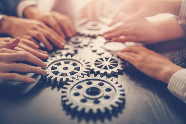 istock People joining cog wheel on the black desk. 1650286568