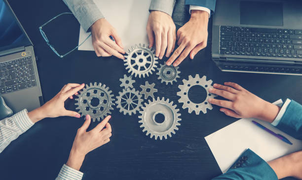 istock People joining cog wheel on the black desk. 1650287100