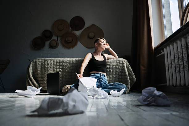 istock Woman professional content writer working with papers and laptop computer at home while sitting on the floor. 1650294332