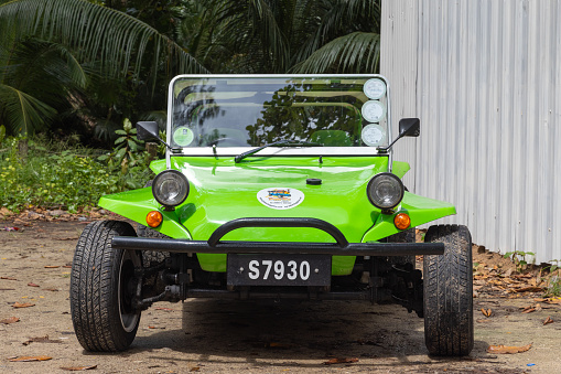 Mahe, Seychelles - August 7, 2023: Front view of a green black beach buggy standing parked on a sunny day