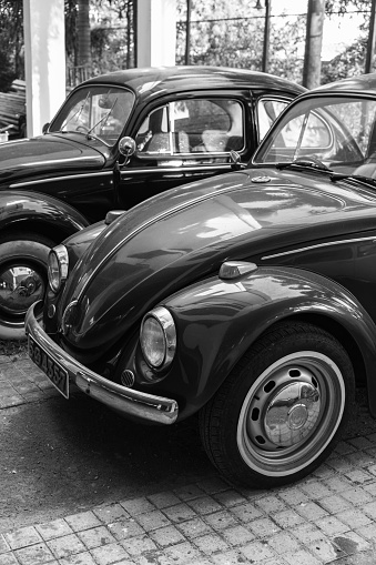 Colombo, Sri Lanka - November 30, 2021: Vintage Volkswagen Kafer cars stand parked on the street. Vertical black and white photo