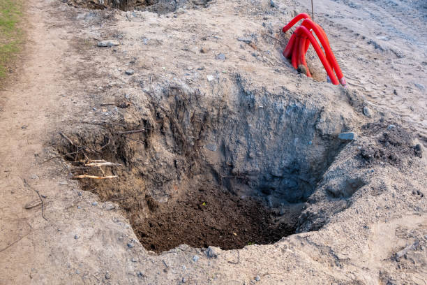 istock Deep pit at the construction site and cables in red flexible pipes 1650326406