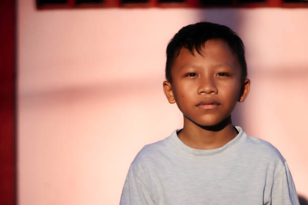 Asian boy, abstract pink background, but looking at him, his expression is not satisfied.