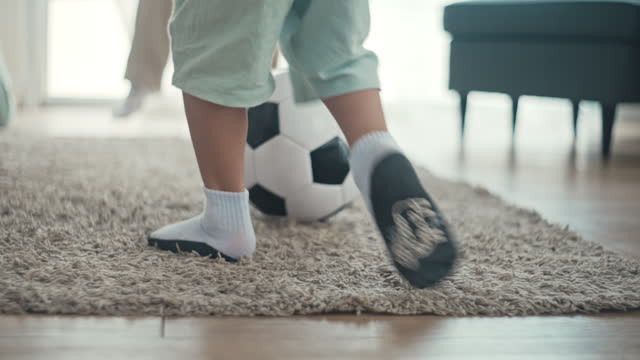 Father and son playing with a football at home