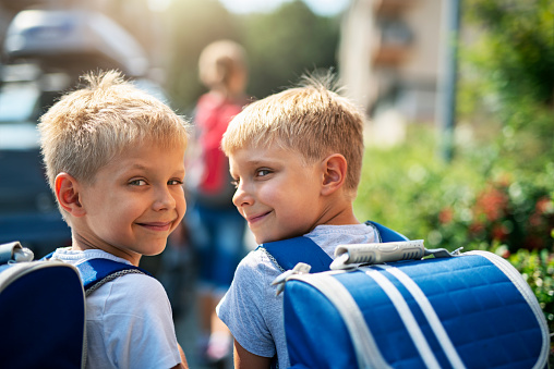 Two little boys walking on a sidewalk on the way to school. Sunny day morning.\nShot with Nikon D850