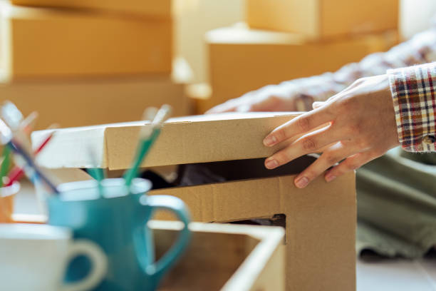 istock Young man holding open cardboard box with things for moving into new house 1650417380