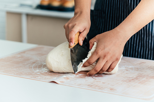 Female pastry chef prepares bread dough in bread kitchen