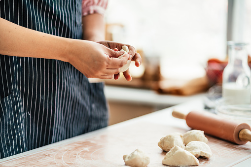 Female pastry chef prepares bread dough in bread kitchen