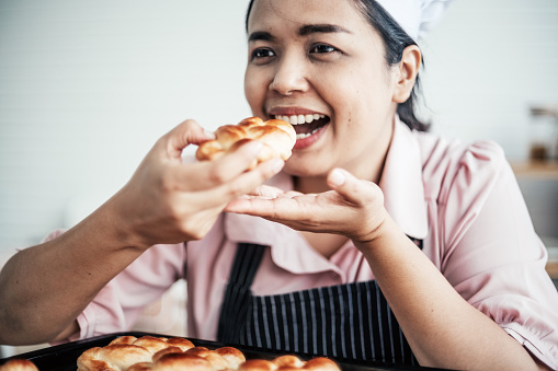 Female baker tasting bread in kitchen
