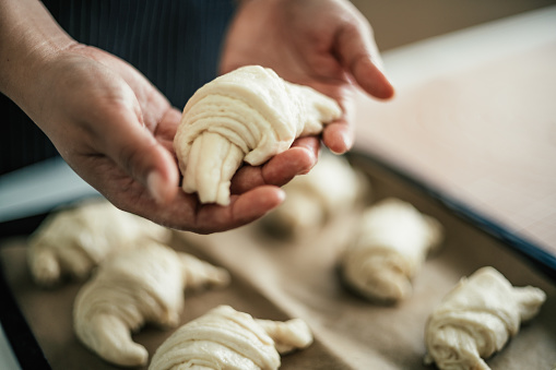 Female baker holding croissant in kitchen