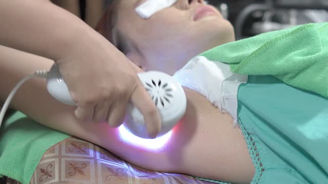 Cryotherapy, Cooling Blue Massager Cryo, Spa treatment and applying cream to the armpit area of an Asian woman in beauty clinics, Medical and cosmetic dermatology appointments concept.