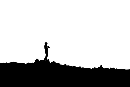 Silhouette of photographer standing with camera taking a photo on the mountain on white background