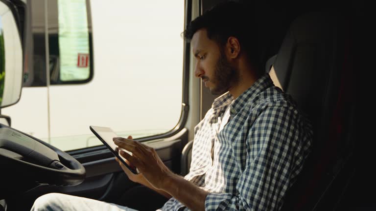 Professional indian trucker using truck gps navigation to transport and deliver goods to the destination. Right hand drive car