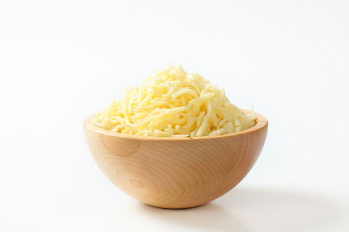 Wooden bowl with grated cheese on white background