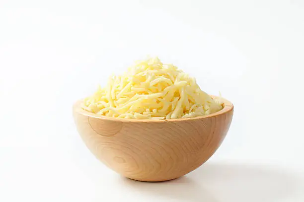 Wooden bowl with grated cheese on white background
