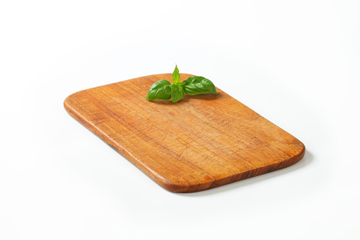 Rectangular cutting board on a white wooden table. Food preparation tool and kitchen utensils. Space for text.