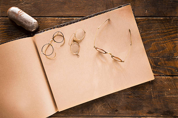 Nostalgia. Vintage desk set up. Antique eyeglasses, old Photo Album, on wooden table.