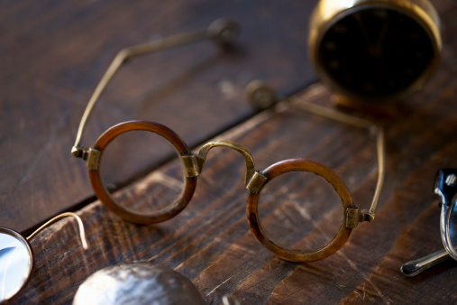 Antique eyeglasses on wooden table. Close-up.The grain and texture added. Selective focus. Very shallow depth of field for soft background.