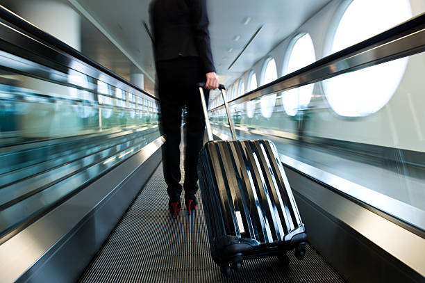 airport walkway Businesswoman at moving sidewalk, taking way to the departure gate. airport travelator stock pictures, royalty-free photos & images