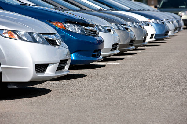 Line of new compact cars at dealership. Lineup of new fuel efficient compact cars in dealership's parking lot, narrow depth of field. car dealership stock pictures, royalty-free photos & images