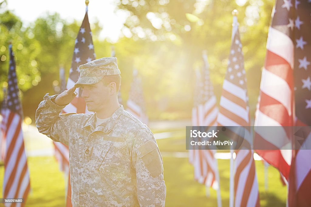 American Soldier American Soldier saluting in front of American flags in the sunset Saluting Stock Photo