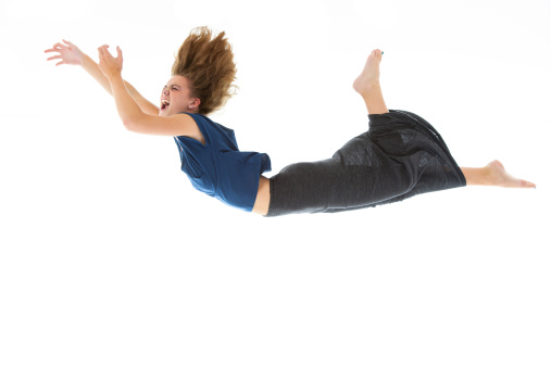 Studio shot, in camera isolation, of a young woman falling through mid-air. Great design element.