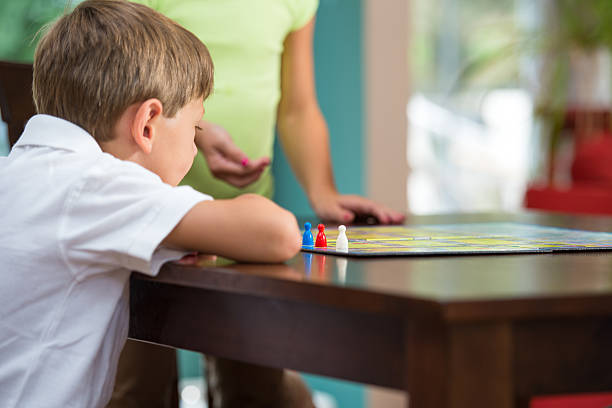 istock Picture of thought and strategy: Young Boy Playing Board Game 165052958