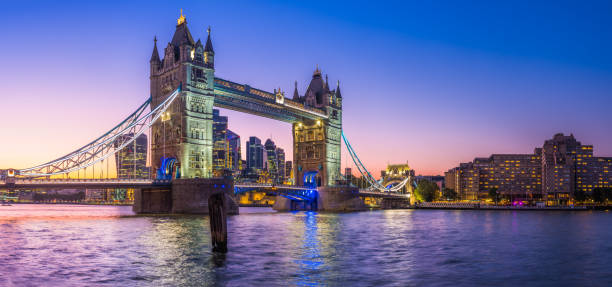 London Tower Bridge City skyscrapers River Thames illuminated sunset panorama The iconic gothic battlements of Tower Bridge framing the modern skyscraper skyline of the City of London illuminated against a dramatic sunset sky over the River Thames in the heart of the UK’s vibrant capital city. central london skyline stock pictures, royalty-free photos & images