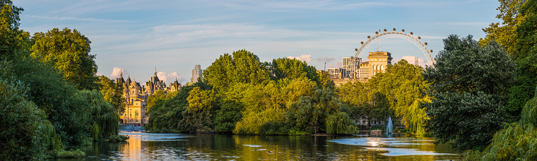 Warm sunset light illuminating the historic towers of Whitehall reflected in the still waters of St. James’s Park Lake in the heart of London, UK.