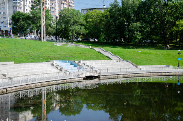 istock Pond surrounded by green trees with a lawn 1650571851