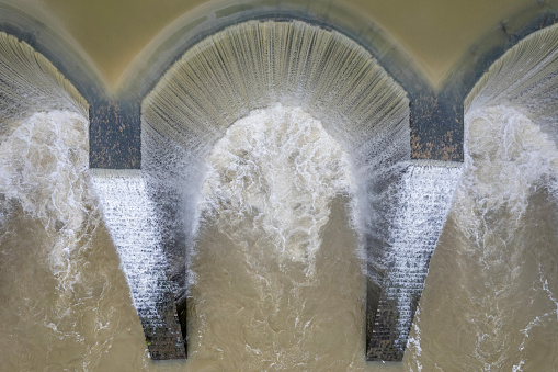 The water overflows the circular reservoir dam