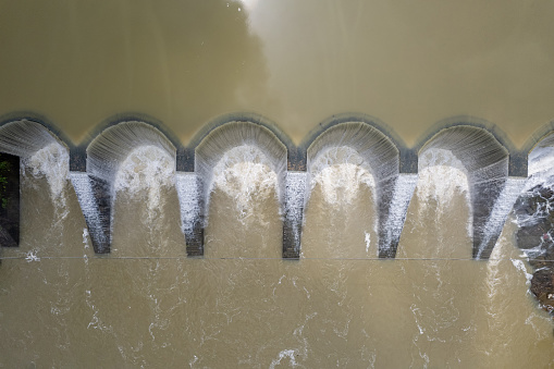 The water overflows the circular reservoir dam