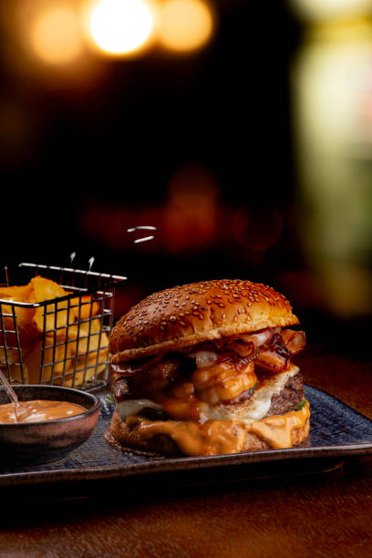 istock burger surf and turf com burger with melted beef cheddar shrimp with cheddar sauce fat black background 1650603039