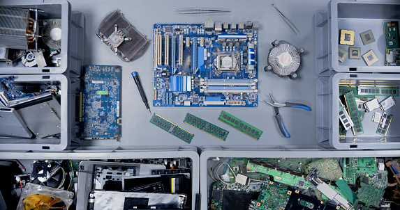 Overhead view of computer equipment's and mother board on desk at recycling centre.