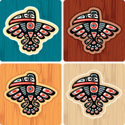 A vector illustration of a crow using a haida-inuit artistic style over differently colored wood textures. The wood texture is complete so you can use it by itself. No gradients.