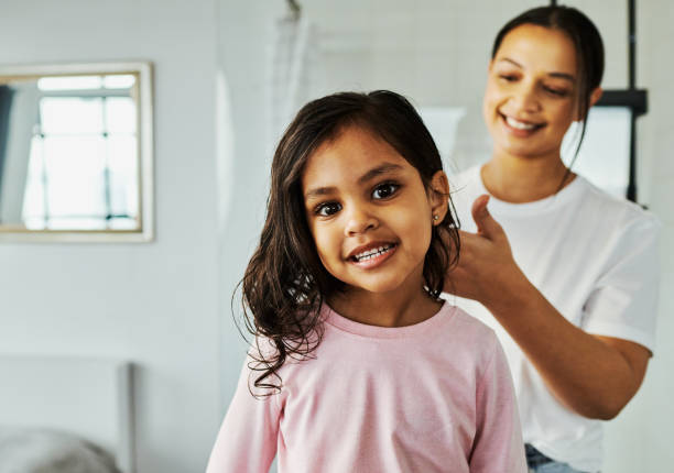 istock Girl smiling bright getting her hair done by mom 1650628471