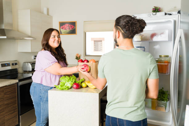 istock Cheerful couple in the kitchen with the open fridge 1650650775