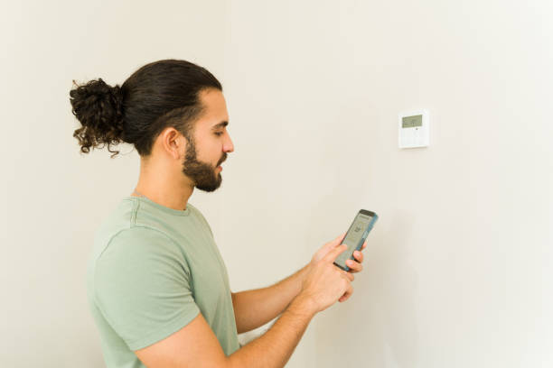 istock Cheerful man turning on the ac using the thermostat 1650663327