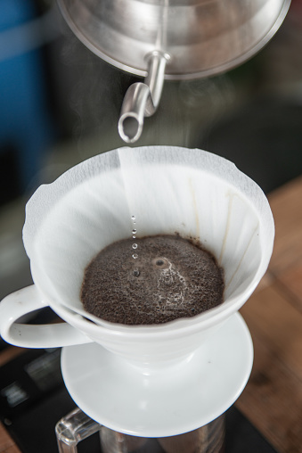 Barista expertly using a drip coffee maker to create a flavorful cup of coffee.