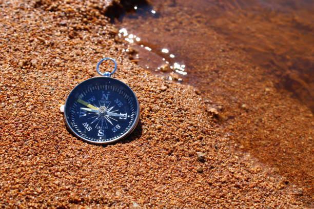 brújula de dirección en la arena de la playa - compass exploration the way forward beach fotografías e imágenes de stock