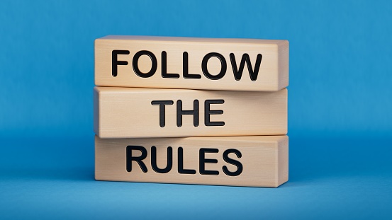 Follow the rules symbol. Concept words Follow the rules on wooden blocks. Business and follow the rules concept. Copy space.3D rendering on blue background.