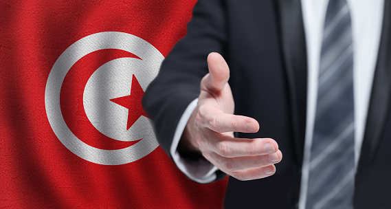 Tunisian business, politics, cooperation and travel concept. Hand on flag of Tunisia background.