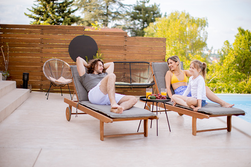 Relaxed young millennial couple enjoying morning coffee and sun-filled conversation on their back deck.