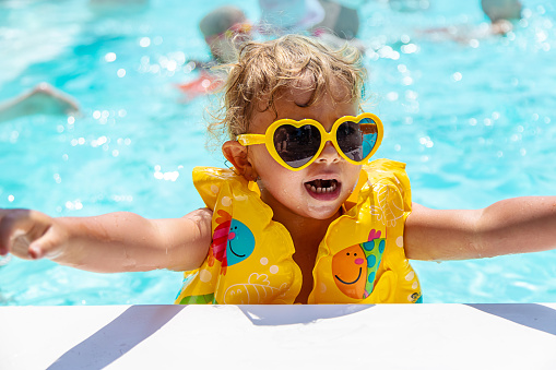The child swims in the pool in a vest. Selective focus. Kid.