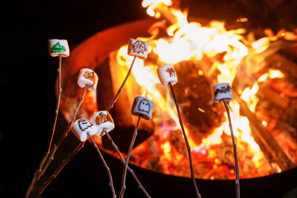 Marshmallows com fotos de Halloween sobre fogo. Lazer engraçado no feriado tradicional assustador para crianças e famílias. - foto de acervo